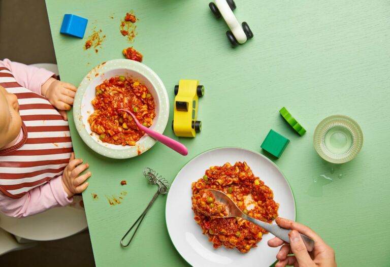 Ruokapöytä, jossa lapsen ja aikuisen italianpatalautanen ja leluja