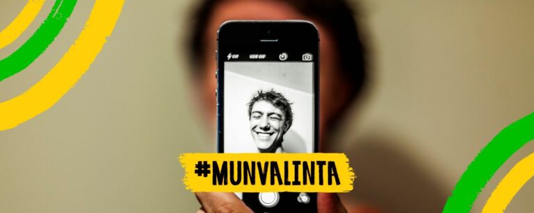 Poikaoletettu henkilö ottaa selfien itsestään. Puhelimen näytöltä näkyy hänen kuvansa. Hän hymyilee. Kuva on muokattu Mun valinta -kampanjan kehyksillä, ja keskellä alareunassa on Mun valinta -kampanjan logo.