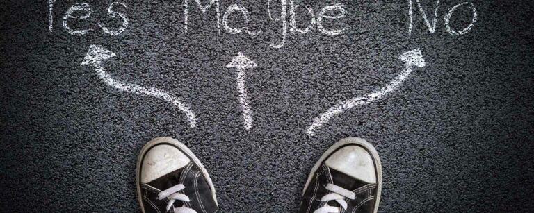 Tennarit asfaltilla, maassa kolme nuolta, joista yksi osoittaa sanaan "yes,", yksi "maybe" ja yksi "no"