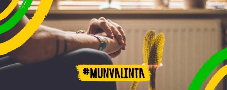 Henkilö istuu kädet ristissä edessään