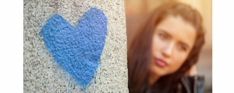 sininen sydän kiviseen pintaan maalattuna, taustalla näkyy naishenkilö