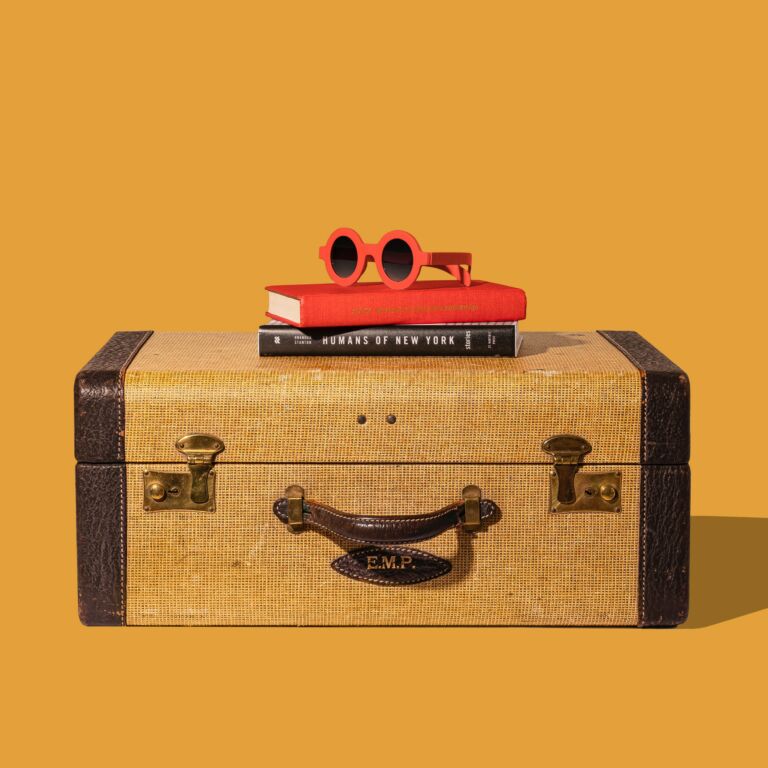 Kuvassa matkalaukku ja sen päällä aurinkolasit ja kaksi kirjaa. Kuva: Unsplash